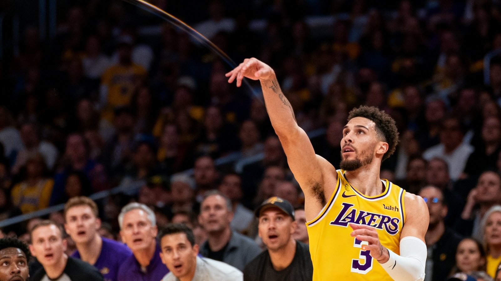 NBA比赛中湖人队球员在终场前0.3秒投出绝杀球，篮球在空中划出弧线，全场观众起立屏息注视